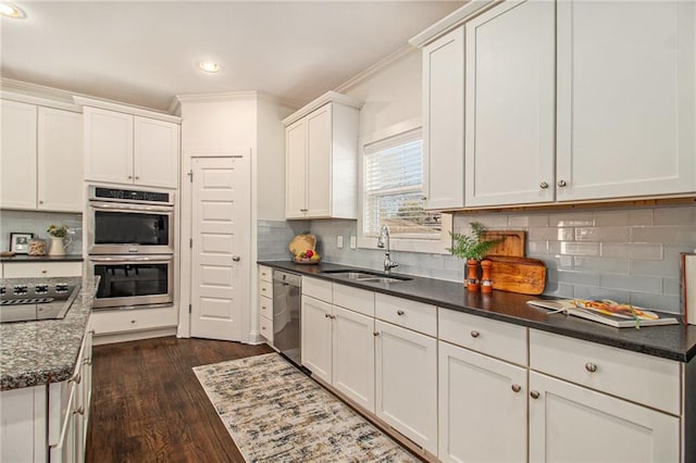 kitchen featuring backsplash, crown molding, stainless steel appliances, white cabinetry, and a sink