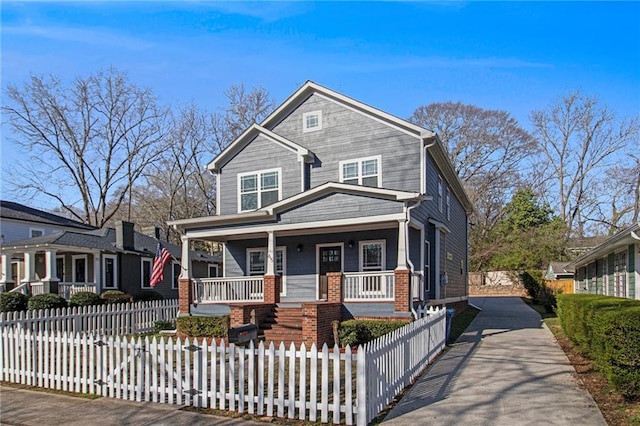 view of front facade with a fenced front yard, brick siding, and covered porch