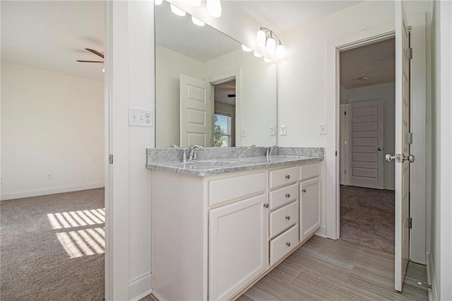 full bath featuring ceiling fan, double vanity, baseboards, and a sink