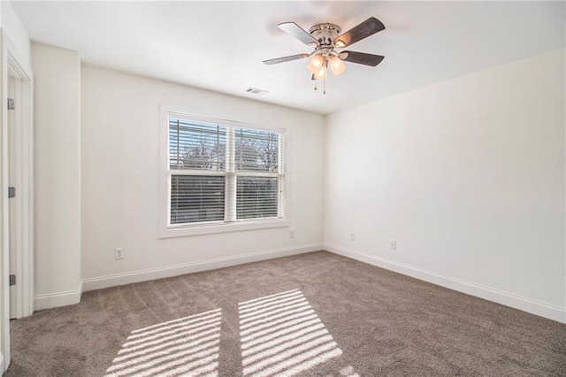 carpeted spare room featuring baseboards, visible vents, and ceiling fan