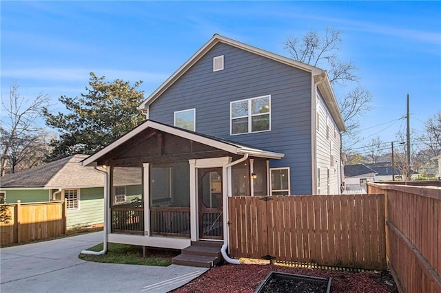 view of front of property featuring concrete driveway, fence private yard, and a sunroom