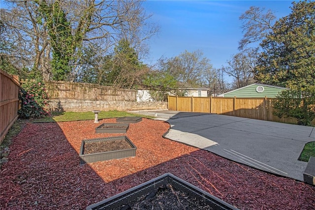 view of yard featuring a garden, a fenced backyard, and a patio area