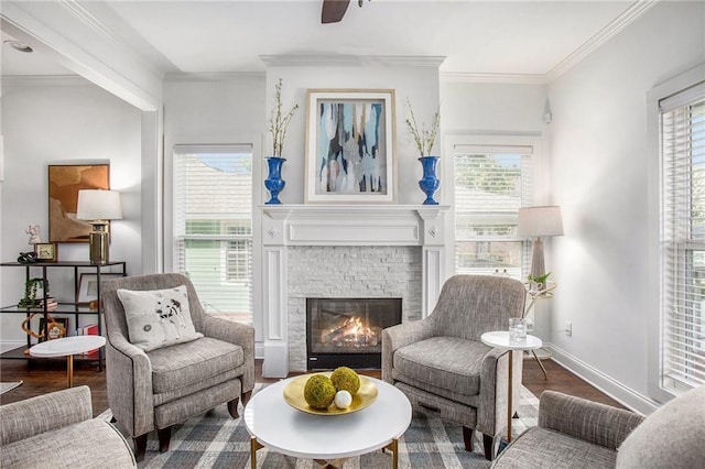 living area featuring a stone fireplace, wood finished floors, baseboards, and ornamental molding