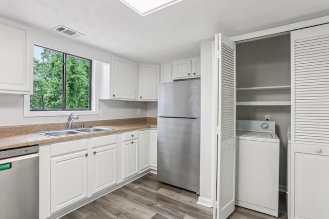 6249 Townsend Way, Riverdale, GA 30296 - kitchen featuring appliances with stainless steel finishes, washer / clothes dryer, white cabinets, wood finished floors, and light countertops