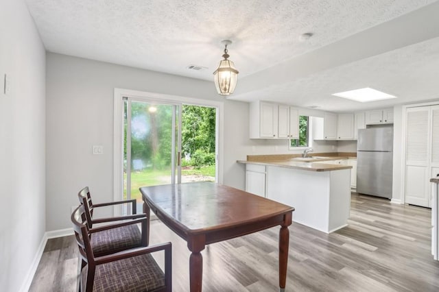 6249 Townsend Way, Riverdale, GA 30296 - kitchen featuring freestanding refrigerator, a textured ceiling, light wood-type flooring, a peninsula, and white cabinets