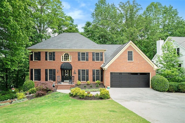 colonial-style house featuring an attached garage, driveway, a front lawn, and brick siding