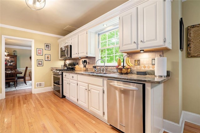 5020 Huntshire Ln SW, Lilburn, GA 30047 - kitchen with appliances with stainless steel finishes, backsplash, white cabinets, and ornamental molding