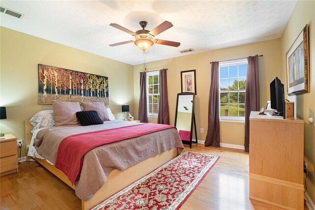 5020 Huntshire Ln SW, Lilburn, GA 30047 - bedroom featuring light wood-style flooring, a textured ceiling, and a ceiling fan