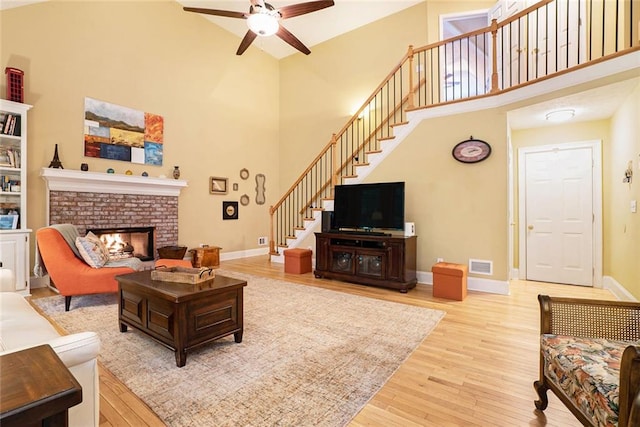 5020 Huntshire Ln SW, Lilburn, GA 30047 - living area featuring a high ceiling, stairway, wood finished floors, ceiling fan, and a fireplace