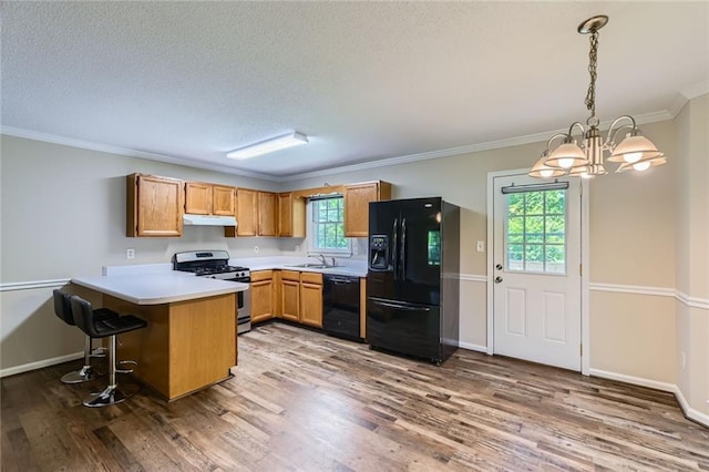62 Sweetwater Pkwy, Powder Springs, GA 30127 - kitchen featuring black appliances, under cabinet range hood, a peninsula, a chandelier, and plenty of natural light