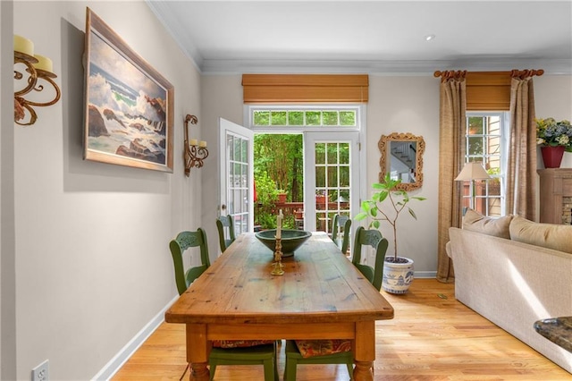 dining area with crown molding, light wood-type flooring, and baseboards