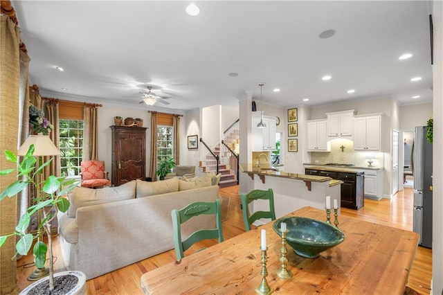 dining area featuring ornamental molding, light wood-type flooring, recessed lighting, stairway, and a ceiling fan