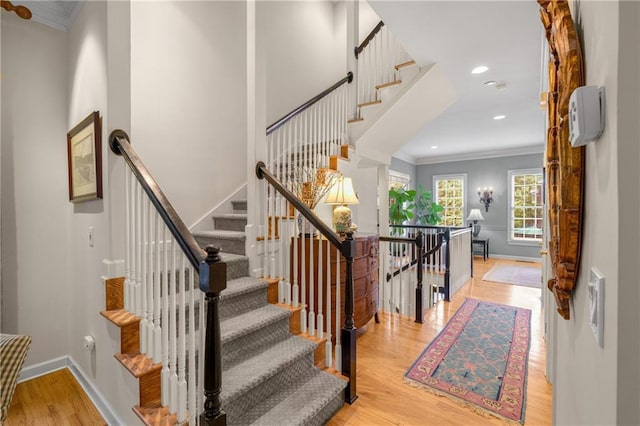 stairway featuring wood finished floors, baseboards, ornamental molding, and recessed lighting