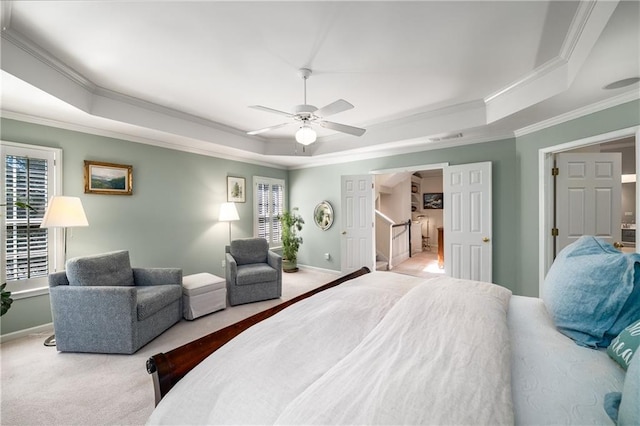 carpeted bedroom featuring crown molding, visible vents, baseboards, a raised ceiling, and ceiling fan