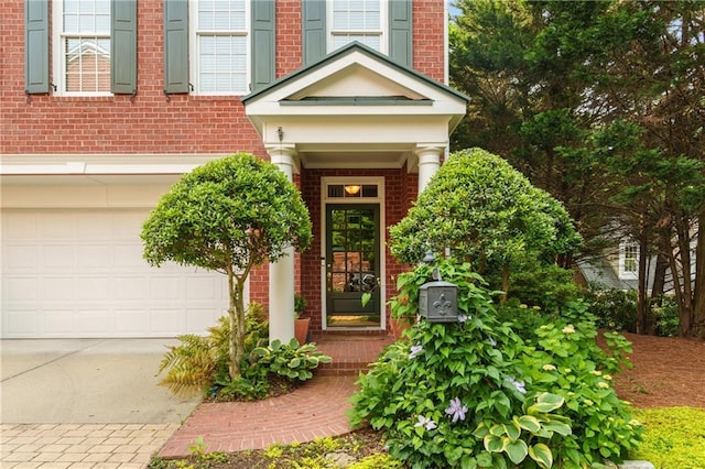entrance to property featuring brick siding, driveway, and a garage