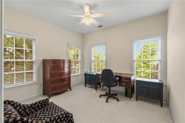 office space featuring light colored carpet, visible vents, baseboards, and a ceiling fan