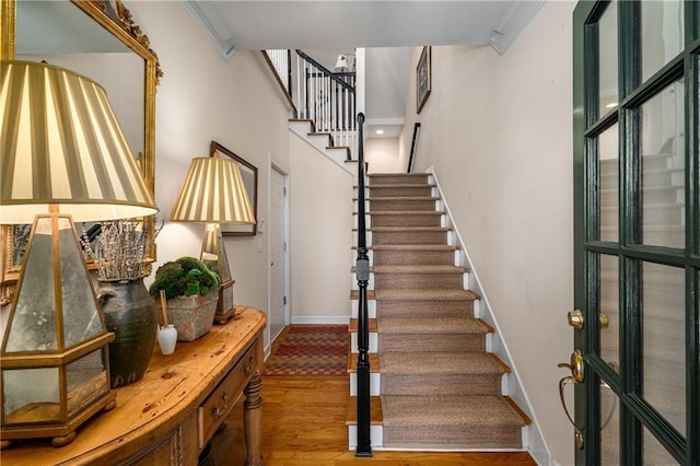interior space featuring baseboards, stairs, a high ceiling, and wood finished floors