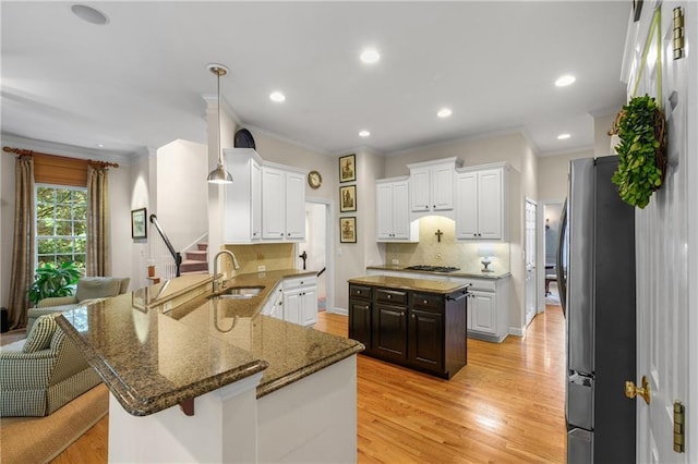 kitchen with a sink, a peninsula, stainless steel appliances, and tasteful backsplash