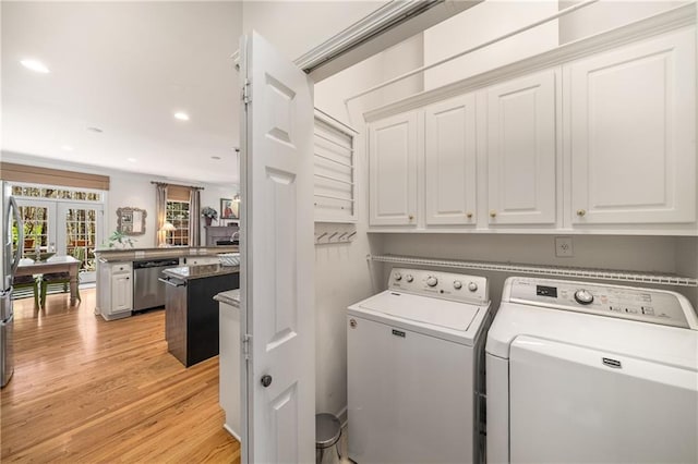 washroom featuring washing machine and clothes dryer, light wood-style flooring, cabinet space, and french doors