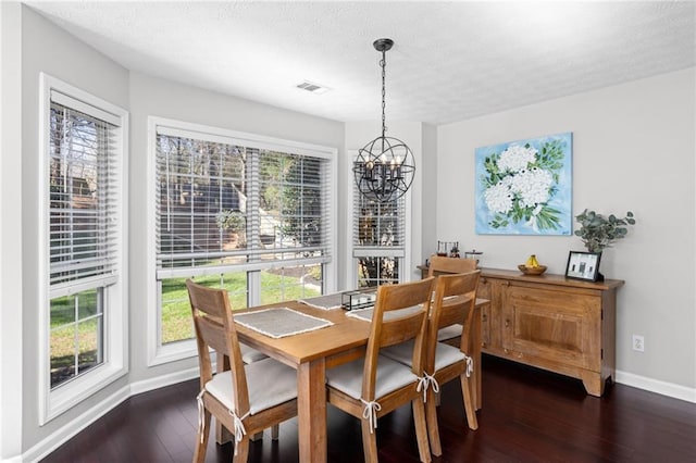 dining area with a chandelier, dark wood finished floors, a textured ceiling, and baseboards