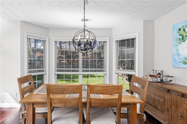 dining room with visible vents, a notable chandelier, wood finished floors, and a textured ceiling