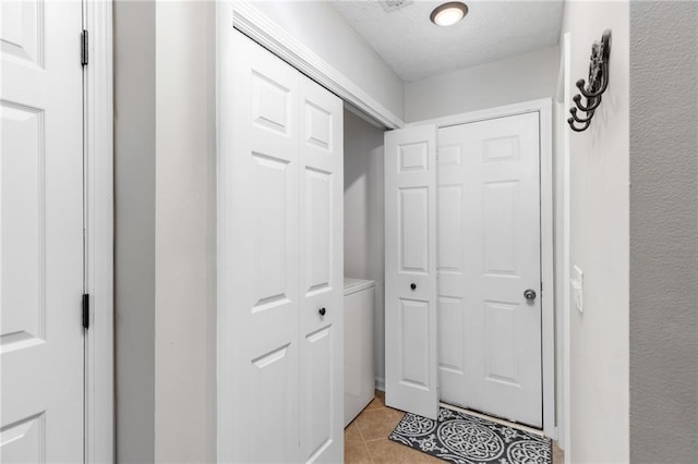 doorway with light tile patterned floors and a textured ceiling