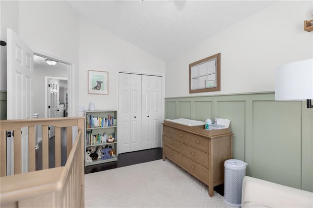 bedroom with a closet, a decorative wall, a wainscoted wall, and vaulted ceiling