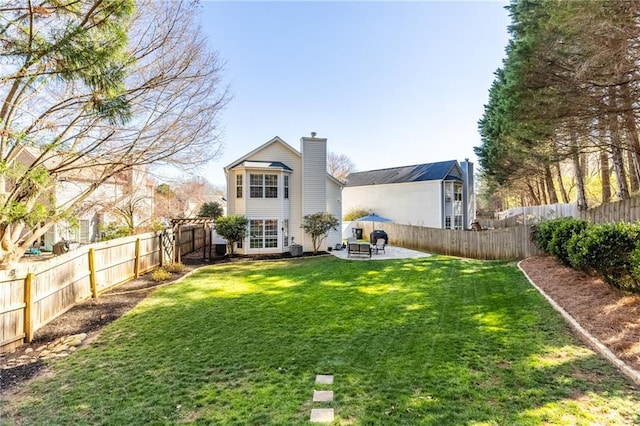 rear view of house with a patio, a yard, a fenced backyard, and a chimney