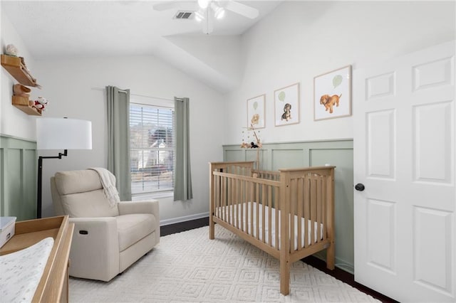 bedroom featuring visible vents, light wood finished floors, ceiling fan, a crib, and vaulted ceiling