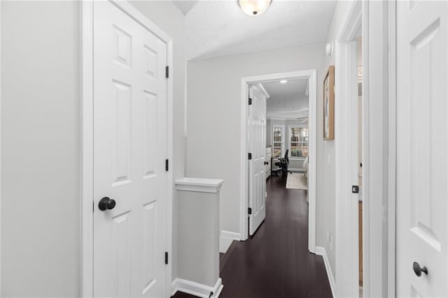 hallway with baseboards, an upstairs landing, a textured ceiling, and dark wood-style floors