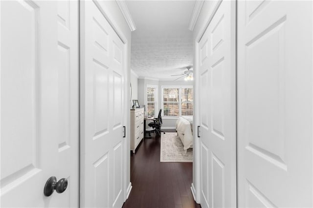 corridor with a textured ceiling, dark wood-style floors, and crown molding