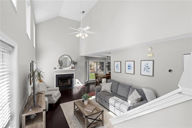 living area with a fireplace with flush hearth, high vaulted ceiling, a ceiling fan, wood finished floors, and baseboards