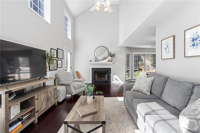 living room with dark wood finished floors, a fireplace, a ceiling fan, and vaulted ceiling