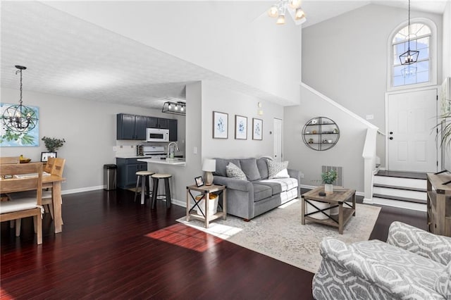 living area featuring stairs, baseboards, dark wood-style flooring, and high vaulted ceiling