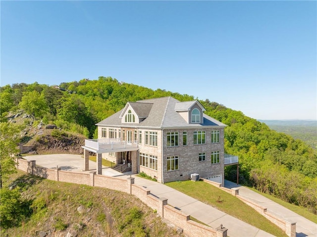 back of house featuring central AC, a balcony, and a garage