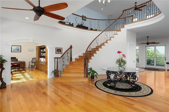 stairs with hardwood / wood-style floors, ceiling fan, and a high ceiling