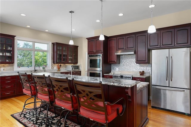 kitchen featuring stainless steel appliances, a center island, a kitchen bar, and light stone counters