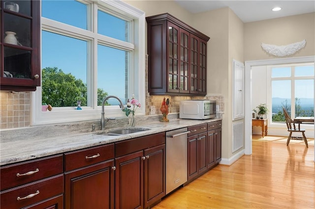 kitchen featuring dishwasher, sink, light stone counters, and light hardwood / wood-style flooring