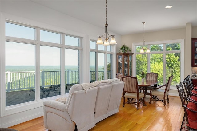 living room with a chandelier, a wealth of natural light, and light wood-type flooring