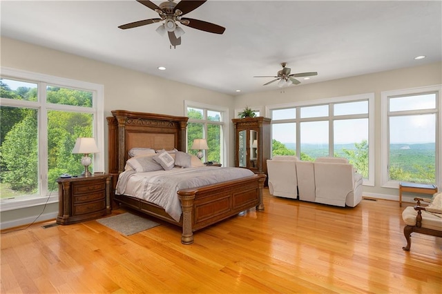 bedroom with multiple windows, light hardwood / wood-style floors, and ceiling fan