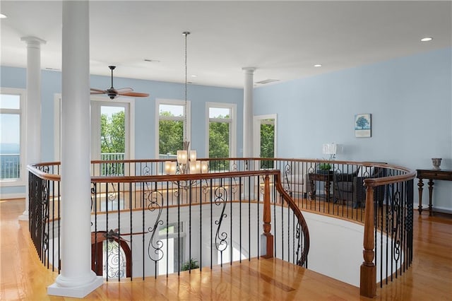 staircase featuring hardwood / wood-style floors, a notable chandelier, and ornate columns