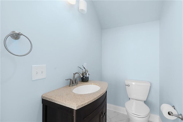 bathroom featuring vanity, lofted ceiling, and toilet