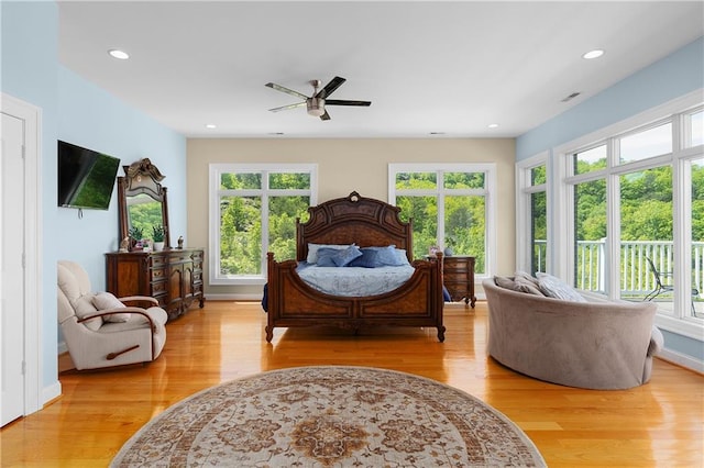 bedroom with ceiling fan, multiple windows, and light hardwood / wood-style flooring