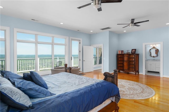 bedroom with hardwood / wood-style flooring, a water view, access to outside, and ensuite bath