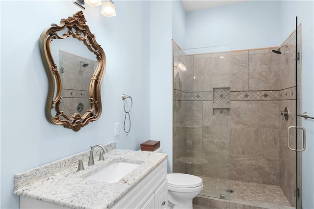 bathroom with vanity, a shower with door, and toilet