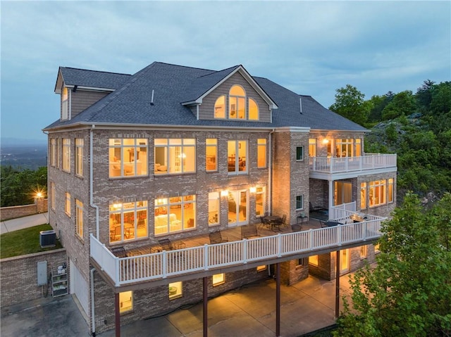 back house at dusk with a balcony and central AC unit