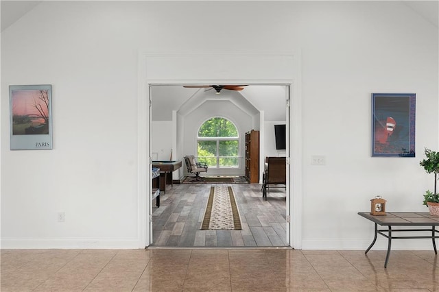 hallway with light tile patterned flooring and lofted ceiling