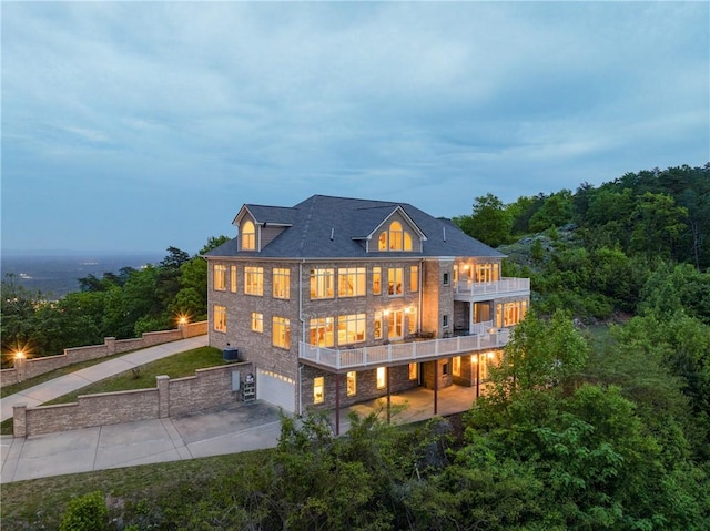 back house at dusk with a garage and a balcony