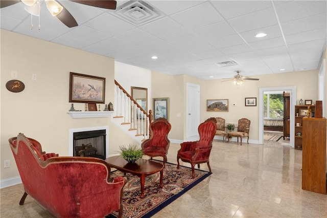 living room with a drop ceiling and ceiling fan