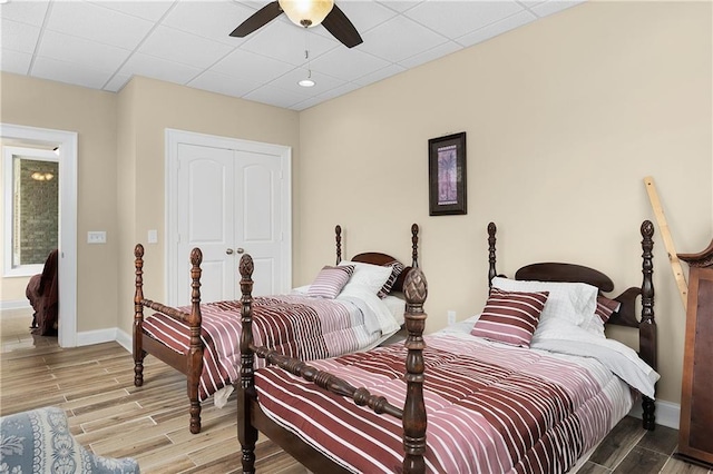 bedroom with wood-type flooring, a paneled ceiling, and a closet